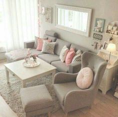 a living room with gray couches and pink pillows on the walls, white coffee table