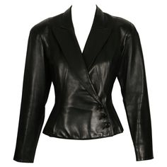 Jet-black, butter-soft leather jacket designed by Azzedine Alaia dating to late 1980's. Jacket has a very flattering silhouette with a fitted waist, slightly flared hemline and beautiful topstitched seams. Labeled a French size 38. Approximate measurements: shoulder 16", bust 34", waist 28.5", arm length from shoulder seam to cuff 23" and overall length at center back (with collar) 22". Button closure. Fully lined. Made in France. Very good condition. Alaia 1992, Azzedine Alaia, Black Leather Jacket, Jacket Design, Jet Black, Made In France, Soft Leather, Overalls, Black Leather