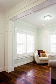 an empty living room with hard wood floors and white trim on the walls, along with two couches