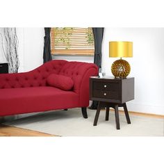 a red couch sitting next to a night stand