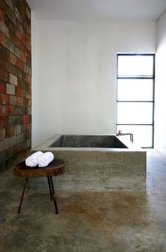 a bathroom with a large bath tub next to a wooden table and two towels on it