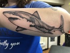 a woman is showing off her arm with a shark tattoo on it