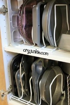 an organized kitchen cabinet filled with pots and pans