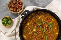 a pot filled with beans and bacon next to other dishes