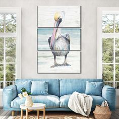 a living room with a blue couch and three paintings on the wall, including a pelican