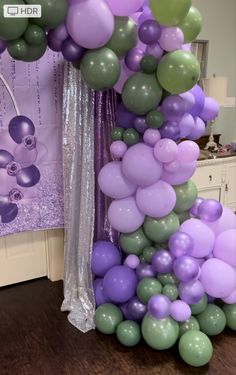 the balloon column is decorated with purple, green and lavender balloons for a birthday party