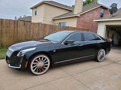 a black car parked in front of a house with its wheels on the rims