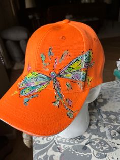 an orange hat with a dragonfly embroidered on it