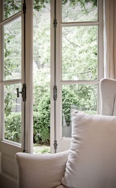 a white chair sitting in front of a window next to a pillow on top of a table