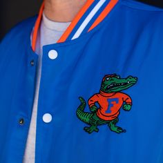 To create this vintage-inspired bomber jacket with varsity vibes, we took this retro Gators logo used from 1955-1994 and paired it with the famous script “Gators” we all know and love. Brought to you in partnership with College Vault. Varsity Jacket With Logo Patch And Baseball Collar, Collegiate Varsity Jacket With Logo Patch For College, College Varsity Jacket With Logo Patch, Collegiate Varsity Jacket With Embroidered Patch For College, Throwback Varsity Jacket For Game Day, Retro Varsity Jacket With Embroidered Patch For Streetwear, Sporty Varsity Jacket With Baseball Collar For Fans, Collegiate Varsity Jacket With Logo Patch For Streetwear, Retro Varsity Jacket For Baseball Season