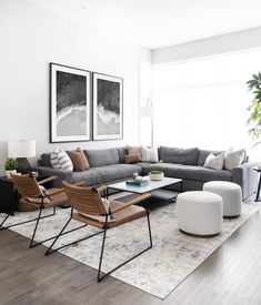 a living room with grey couches and white rugs on top of the floor