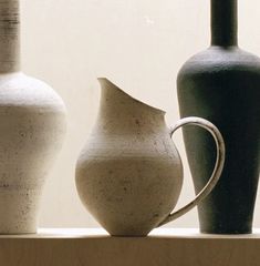 three vases sitting on top of a shelf in front of a window sill