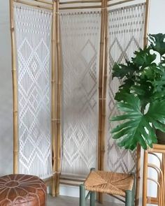 a room divider made out of bamboo with two chairs next to it and a potted plant in the corner