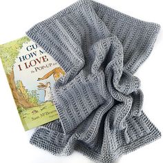 a gray knitted scarf with a book on the front and an image of a squirrel