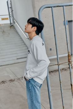 a young man standing in front of a metal hand rail with his back to the camera