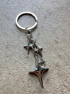 a metal keychain with two star charms on it's sides, hanging from a chain