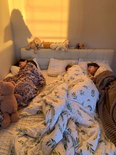 two children sleeping in bed with teddy bears on the side and blankets covering them from the sun