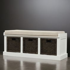 a white bench with wicker baskets under it and a black wall in the background