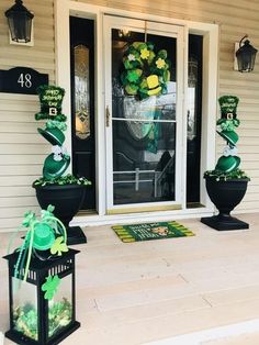 a front porch decorated for st patrick's day with potted plants and lanterns