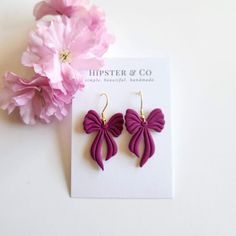 These raspberry colored bow dangle earrings are super lightweight and a great statement accessory. These earrings are handmade out of a purple polymer clay in small batches. Dimensions: Length: approximately 2 inch Width (at widest point): approximately 1 inch Materials Polymer clay Gold-finished stainless steel fish hook Resin PLEASE NOTE Each earring is handmade and so dimensions may differ slightly. Colors may differ based on computer settings. Elegant Purple Polymer Clay Earrings, Purple Polymer Clay Earrings, Raspberry Color, Purple Bows, Black Bow, Fish Hook, Gold Finish, Raspberry, Polymer Clay