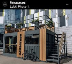 there is a small building made out of shipping containers with plants on the top and stairs leading up to it