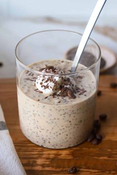 a close up of a dessert in a glass on a wooden table with coffee beans