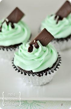 three cupcakes with mint green frosting and chocolate on top, sitting on a white plate