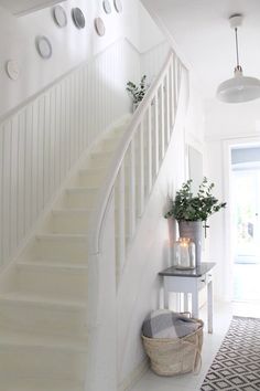 a white staircase leading up to a living room with potted plants on the side