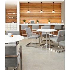 a room filled with lots of white tables and chairs next to each other in front of a wooden wall