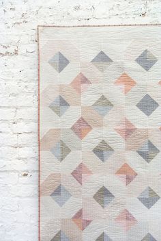 a white brick wall with a quilt hanging on it