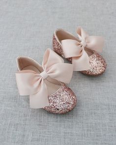 two pairs of baby shoes with bows on them