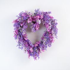 a heart shaped wreath with purple and white flowers in the shape of a heart on a white background