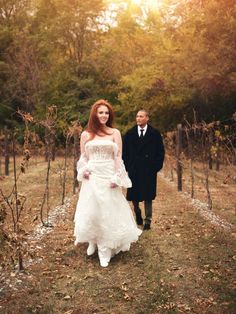 a bride and groom walking through the vineyard at their wedding ceremony in autumn, with leaves on the ground