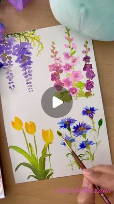 someone is painting flowers with watercolors on paper