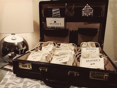 an open suit case sitting on top of a bed next to a lamp and lampshade