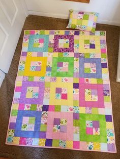 a colorful quilt is laying on the floor next to a white door and brown carpet