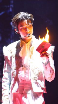 a man with headphones on holding a red object in his hand while wearing a white suit