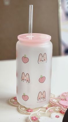 a pink cup with stickers on it sitting on a table next to other items