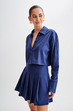 Buttoned and ready. Introducing the JULIANNA Cotton Button Up Shirt in Navy, a versatile staple for every wardrobe. With its collared neckline and functional center front placket with button closure, this shirt exudes timeless sophistication. The cropped length adds a modern twist, while long sleeves and functional cuffs offer both style and practicality. Crafted from breathable, unlined cotton, it ensures comfort all day long. Complete with a back inverted box pleat and back yoke details, this shirt combines classic elements with contemporary flair. Whether dressed up the Julianna Cotton Pleated Mini Skirt or dressed down with jeans, the Julianna Cotton Button Up Shirt is a versatile piece that effortlessly elevates any outfit. Semi-formal Fitted Top With Collared Neckline, Semi-formal Collared Tops For Spring, Chic Single Breasted Tops For Business Casual, Fitted Collared Neckline Top For Semi-formal Occasions, Fitted Semi-formal Tops With Collared Neckline, Chic Shirt With Button Cuffs And Collared Neckline, Fall Button-up Tops With Hidden Button Closure, Collared Shirt For Day Out In Fall, Collared Shirt With Button Cuffs For Day Out