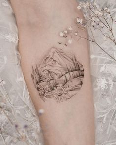 a woman's arm with a mountain scene tattoo on the left side of her body