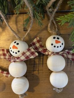 two snowman ornaments hanging from a christmas tree