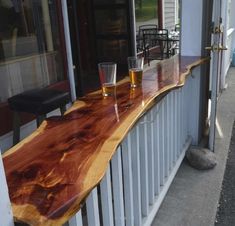 two glasses sitting on top of a wooden counter next to a building with windows and doors