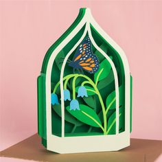 a card with a paper cut out of a butterfly in a birdcage and blue flowers