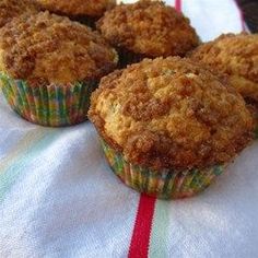 three muffins sitting on top of a white cloth covered in crumbs