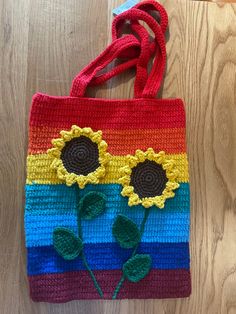 a crocheted bag with two sunflowers on it sitting on a wooden floor