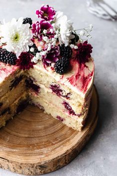 a cake with berries and flowers on top is cut in half to show the layers