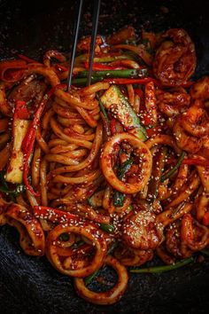 the stir fry is being cooked in a wok with chopsticks and sauce