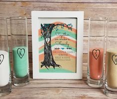 three shot glasses sitting on top of a table next to a picture frame and two candles