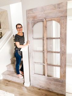 a woman standing in front of a wooden door with glass inserts on the side