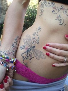 a woman with tattoos on her stomach wearing a pink bra and matching bracelets,